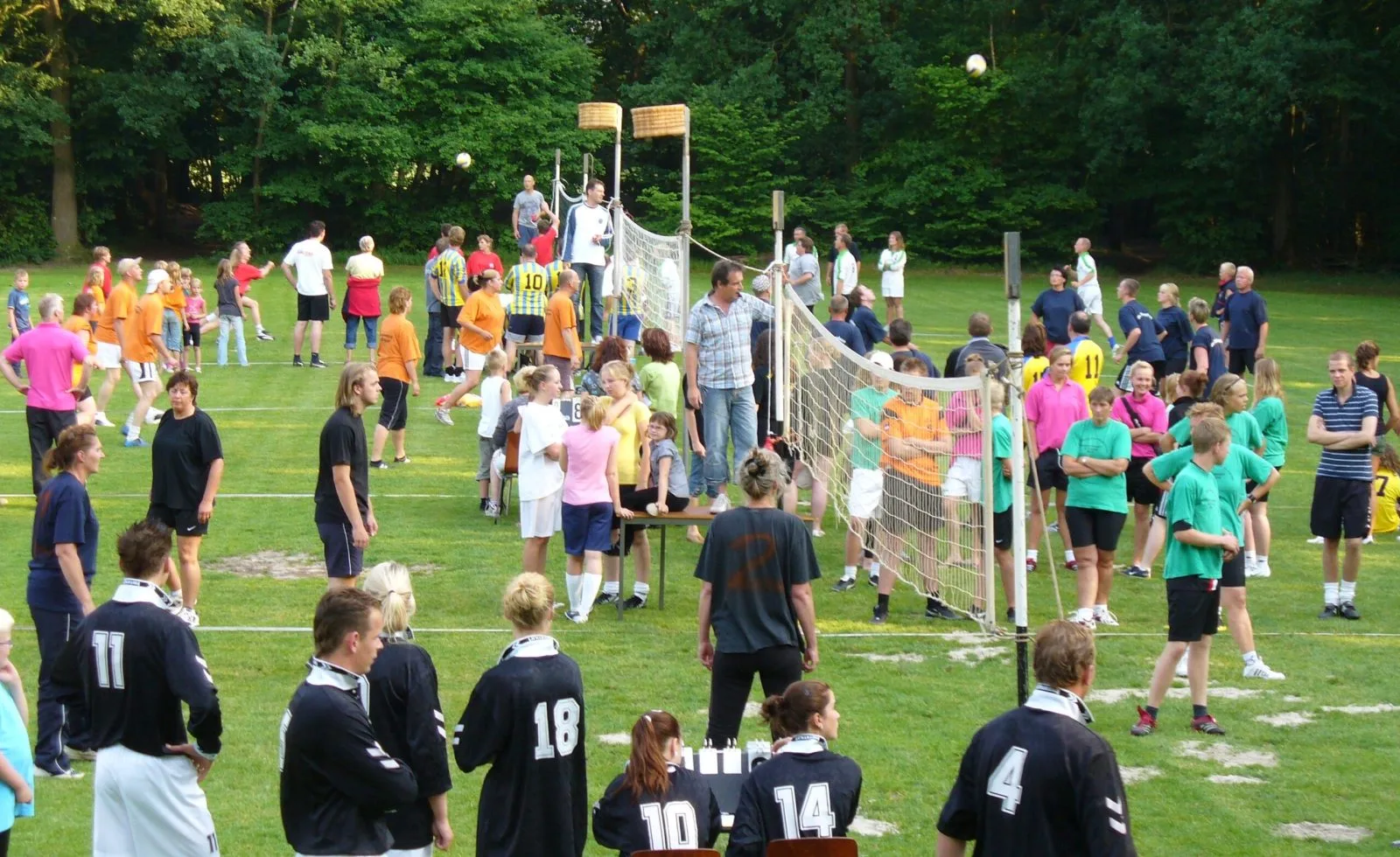 Volle sportvelden van Wees Kwiek in Nuis tijdens het stratenvolleybaltoernooi, met de korven op de achtergrond